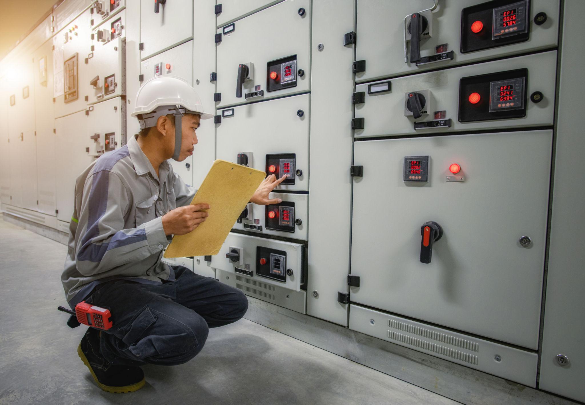 Technician inspecting an electrical switchgear panel