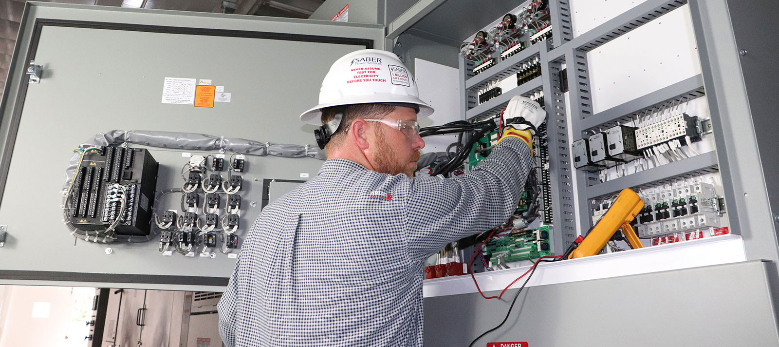 Technician performing pre-commissioning inspection on an electrical control panel